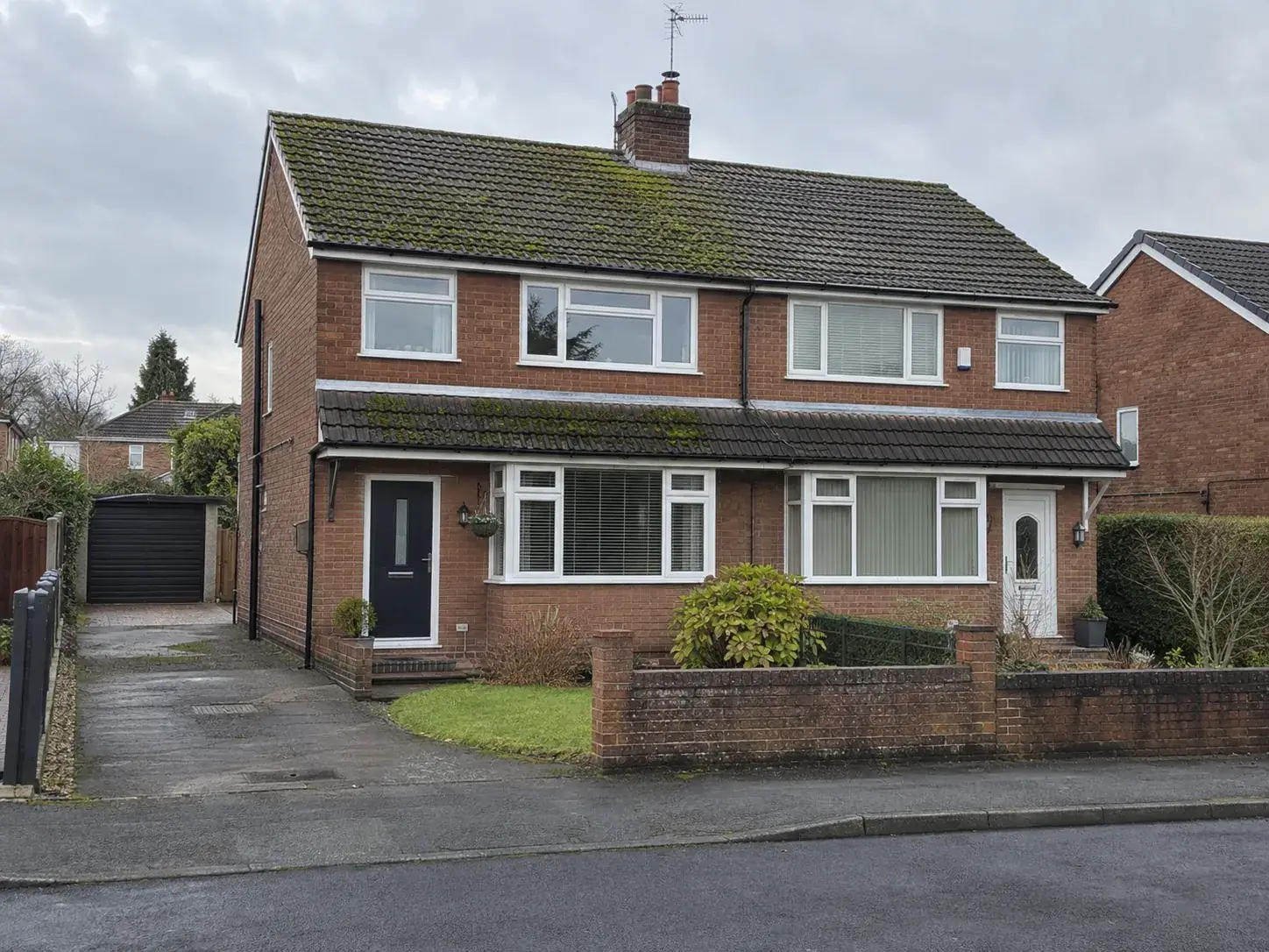 Semi-detached house with a moss-covered roof before cleaning